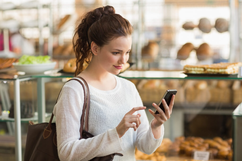 pretty brunette sending a text at the bakery